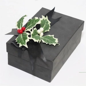 Black Christmas gift box with red foam berries, green holly leaves and a satin ribbon