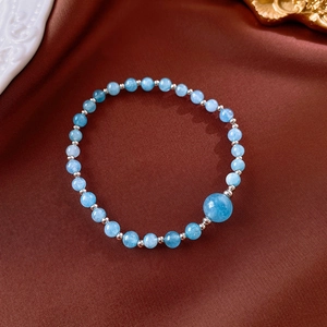 Macro detail of beaded Shoushan stone bracelet with light blue beads on red velvet