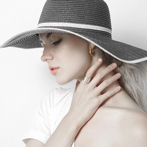 Close-up of a model wearing golden knot hoop earrings with a wide silver layered ring