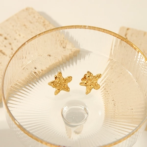 Vue détaillée de boucles d'oreilles étoile de mer dorées avec surface texturée