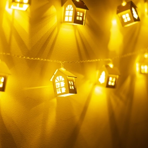 Detailed close-up of warm glowing wooden house-shaped LED fairy lights on a wall