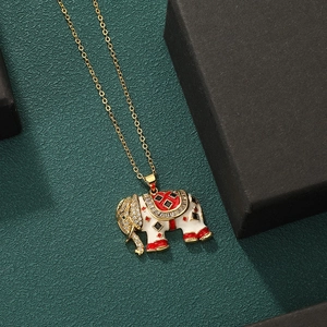 Elegant gold elephant necklace with white enamel and sparkling zircon on green background