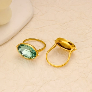 Close-up of golden stainless steel rings with large oval green crystal stones and faceting