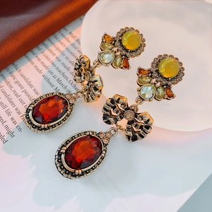 Macro detail of vintage gold earrings with red gems and bow knot on antique paper