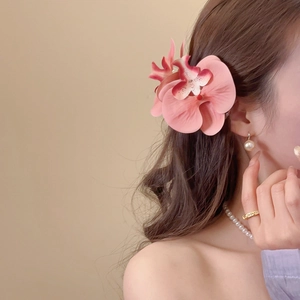 Detail of pink fabric orchid hair clip with realistic petal texture on a model