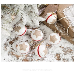 Close-up of white Christmas foam balls with red ribbons and wood stars on faux snow