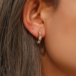 Gold bamboo-style ear cuff hoop earrings with baguette-cut zircons worn by a model
