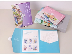 Stack of watercolor painting books with paint palettes and landscape illustrations