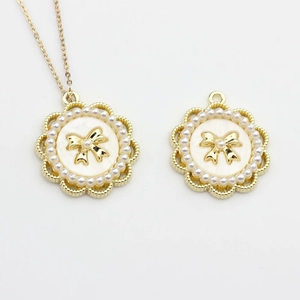 Detailed view of round gold pendants with pearls, white resin and a small bow detail