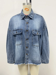 Detail of vintage washed blue denim shirt featuring utility pockets and frayed hemline