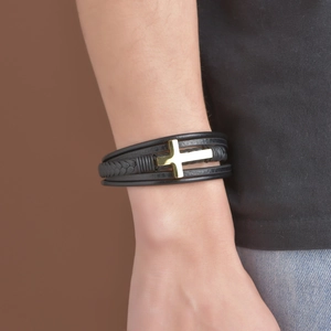 Bracelet multicouche en cuir noir pour homme avec croix dorée porté au poignet du modèle