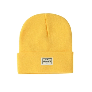 Detail of yellow knit beanie featuring a white Brooklyn N°86 letter patch decoration