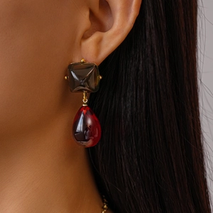 Détail de pierres en résine rouge et marron sur des boucles d'oreilles dorées élégantes