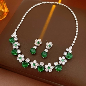 Close-up of zircon flower jewelry set with emerald green stones on leather background