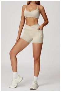 Detail of high-waisted beige yoga shorts featuring a V-cross waistband and side pockets