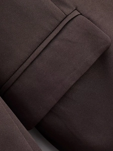 Detail shot of brown double-breasted blazer fabric texture and pocket stitching