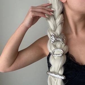 Detailed view of three silver hammered metal hair clips styled on a silver braided ponytail