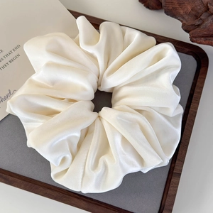 Close-up of a large cream white velvet scrunchie on a tray with French minimalist vibes