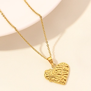 Detail of 18k gold heart pendant featuring embossed daisy flower and hammered texture