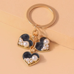 Detailed view of heart-shaped keychain with black marble inlay and white pearl accents