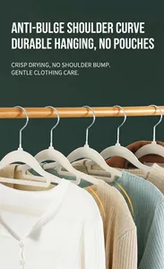 Detail view of white non-slip flocked hangers with wide shoulder support on a wooden rod