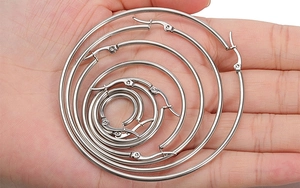 Detailed view of silver hoop earrings in six different sizes shown on a hand for scale