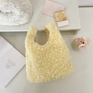 Detailed overhead view of a soft yellow faux fur tote bag on a minimalist desk