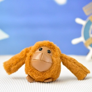 Primo piano di un simpatico portachiavi a forma di orango in peluche marrone con pelo morbido