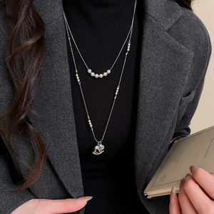 Detail of double-layer pearl necklace with a dainty silver rocking horse pendant on a model