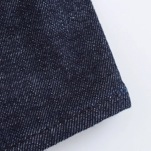 Dettaglio della trama del denim blu scuro e delle cuciture precise sul vestito lungo