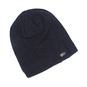 Macro detail of navy knit beanie featuring diamond pattern and Heat metal tag