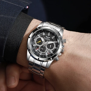 Close-up of silver steel chronograph watch with black dial worn under a business suit sleeve