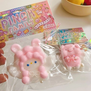 Close-up of pink rabbit and pig pinch toys with packaging and metal chains