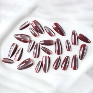 Détail de faux ongles amande longs œil de chat bordeaux profond avec finition brillante