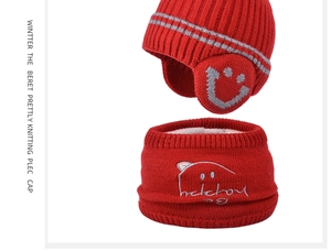 Detail of red knit kids hat and scarf set with thick white fleece lining and smiley patch