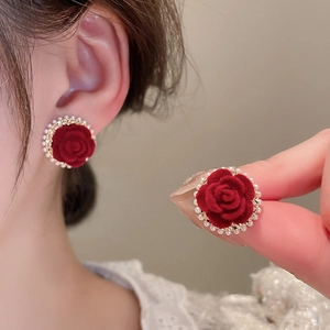 Dettaglio di orecchini a rosa rossa floccata con perle finte e bordo dorato