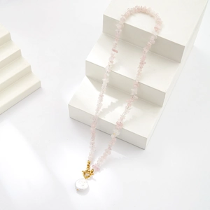 Detailed shot of pink stone beaded necklace with baroque pearl pendant and golden OT clasp