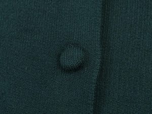 Macro detail of the dark green knitted fabric and matching fabric-covered button texture
