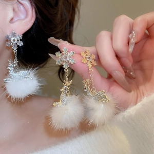 Detail of snowflake deer earrings with white fur balls and rhinestones in silver and gold