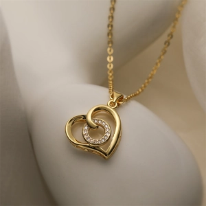 Close-up of gold hollow heart pendant with zircon circle on white minimalist pedestal