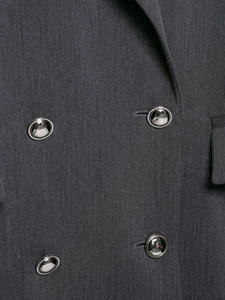 Gros plan détaillé du tissu de blazer gris foncé avec boutons en métal argenté et texture