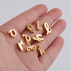 Close-up of golden script alphabet charms for DIY jewelry making held in a palm