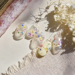 Macro detail of floral nail art stickers with dried flowers and micro pearl accents