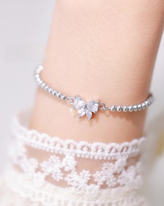 Close-up of sparkling zircon butterfly charm on silver beaded adjustable bracelet