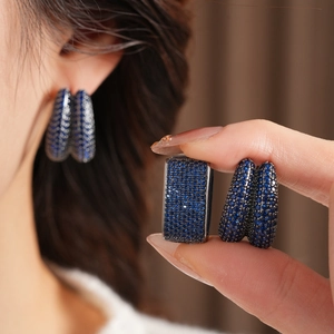 Close-up detail of vintage U-shaped earrings with blue zircons and micro-pave setting