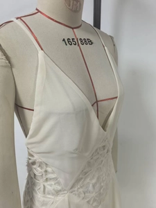 Close-up of white deep V-neck dress featuring intricate 3D lace and textured floral fabric