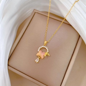Detail of gold necklace featuring a pink butterfly pendant with pearls and crystals