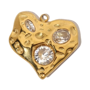 Macro shot of gold heart pendant with embedded zircons and textured stainless steel finish
