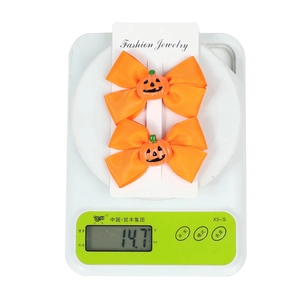 Detail shot of orange Halloween pumpkin hair clips on a scale weighing 14.7g