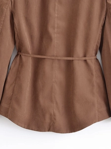 Detail of dark brown blazer featuring a waist tie belt and premium linen fabric texture